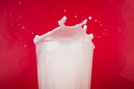 Dramatic splash of milk captured against a vibrant red background.